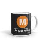 Classic Subway Logo Coffee Mugs | Ceramic mug with a orange circle featuring a white "M". Text below reads: "Manhattan." Perfect for fans of the NYC Subway Line.